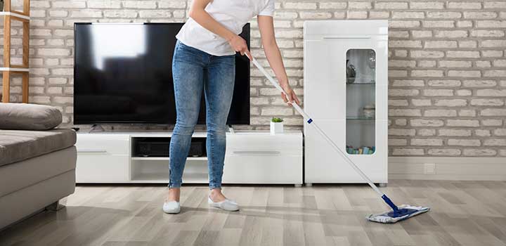 Woman cleaning the hardwood floor of the living room