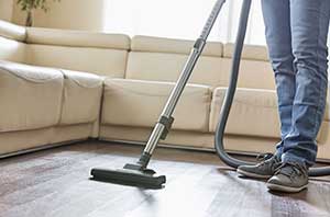 Man cleaning a hardwood floor with a vacuum cleaner